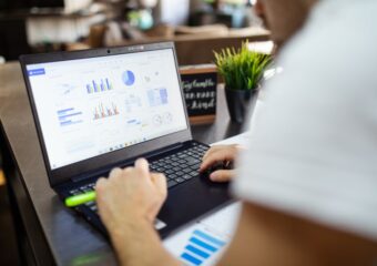 Focused business analysis with charts and graphs on a laptop in a modern office setting.