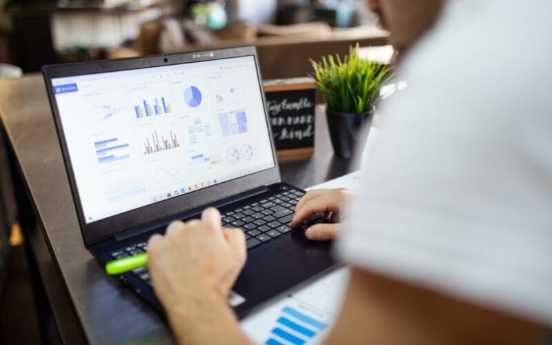 Focused business analysis with charts and graphs on a laptop in a modern office setting.