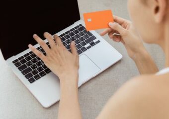 Woman holding credit card making online purchase on laptop computer, representing e-commerce.