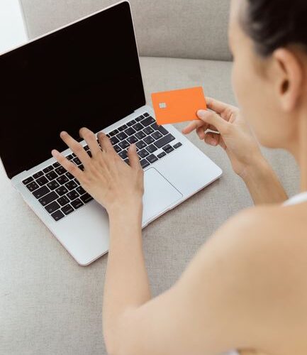 Woman holding credit card making online purchase on laptop computer, representing e-commerce.